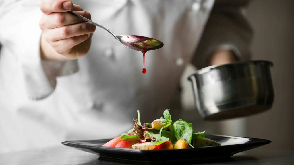 Chef dropping sauce on a plate of food